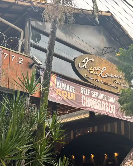 A entrada do Xico da Cidade Nova, com o número 772, o letreiro de madeira e a faixa do self-service com churrasco